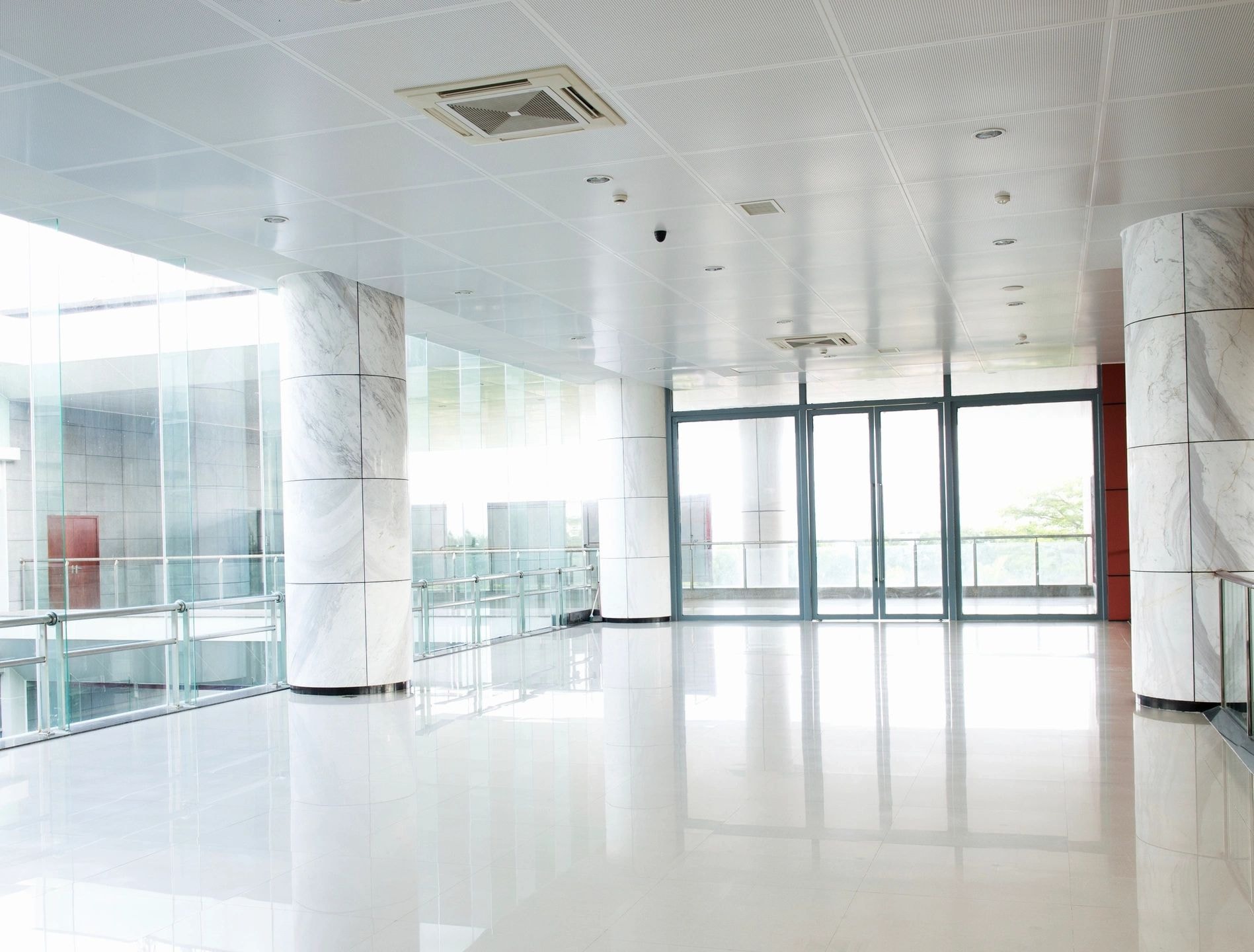 Polished white commercial corridor with marble columns and glass doors