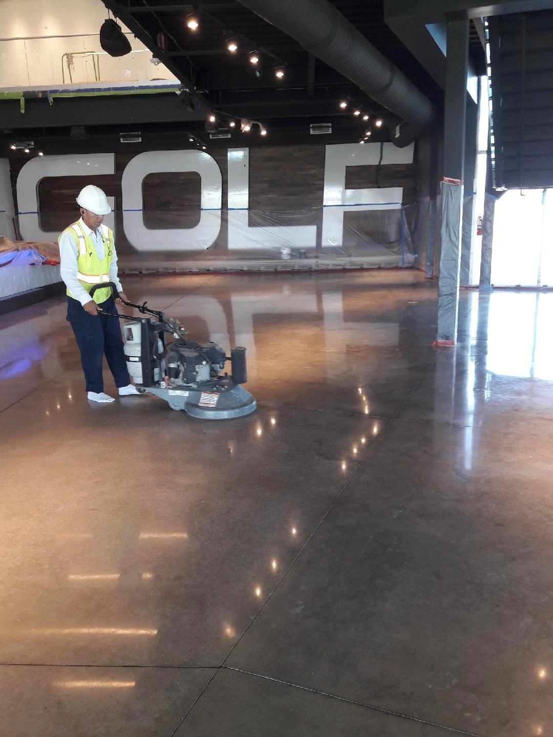 Worker operating concrete floor polishing machine